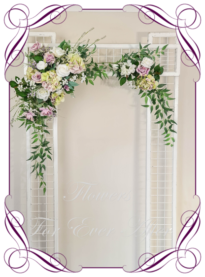 Silk artificial mauve lilac, green and white modern romantic wedding flowers wedding arbor arch background decoration. Hydrangea, white roses lilac roses on a garland, silk wedding florals, unusual romantic realistic fake wedding decoration design. Bridal table centrepiece flowers. Made in Melbourne Australia. Buy online..